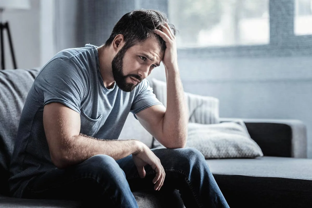 broadwaytreatmentcenter-seasonal-affective-disorder-and-recovery-photo-of-a-Sad-unhappy-handsome-man-sitting-on-the-sofa